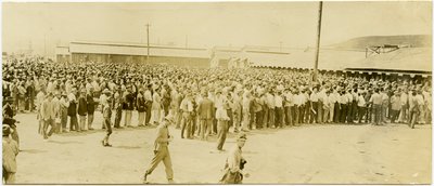 Hundreds of Men in Civilian Clothing Standing in Lines Waiting to Enter Buildings by Carl Michel
